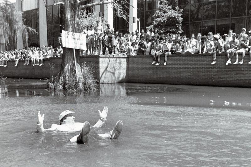 Phil Beridon jumps into Cypress Lake at Lagniappe Day in 1984 while a crowd of students cheers him on.