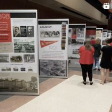 People standing in front of a variety of displays talking about the university