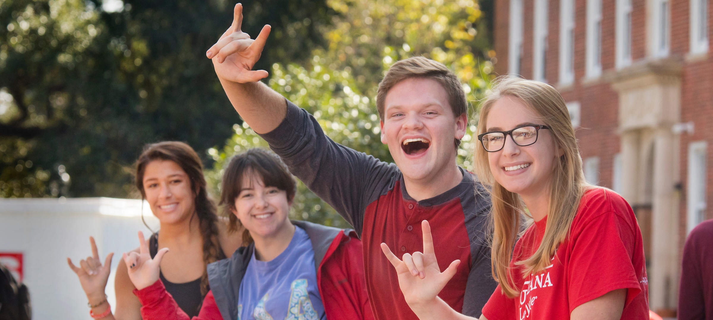 students smiling and making the UL hand sign
