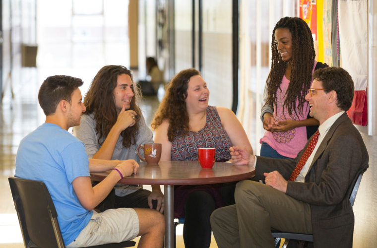 A professor and four students at a French conversation table.