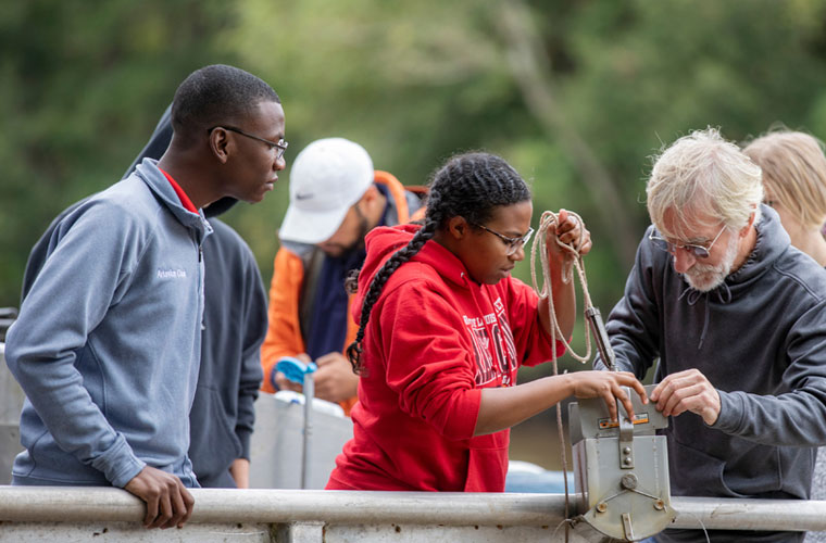 UL Lafayette biology students and faculty getting hands-on experience outside testing water samples at the river
