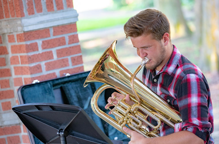 A University of Louisiana at Lafayette student plays his euphonium outdoors on campus