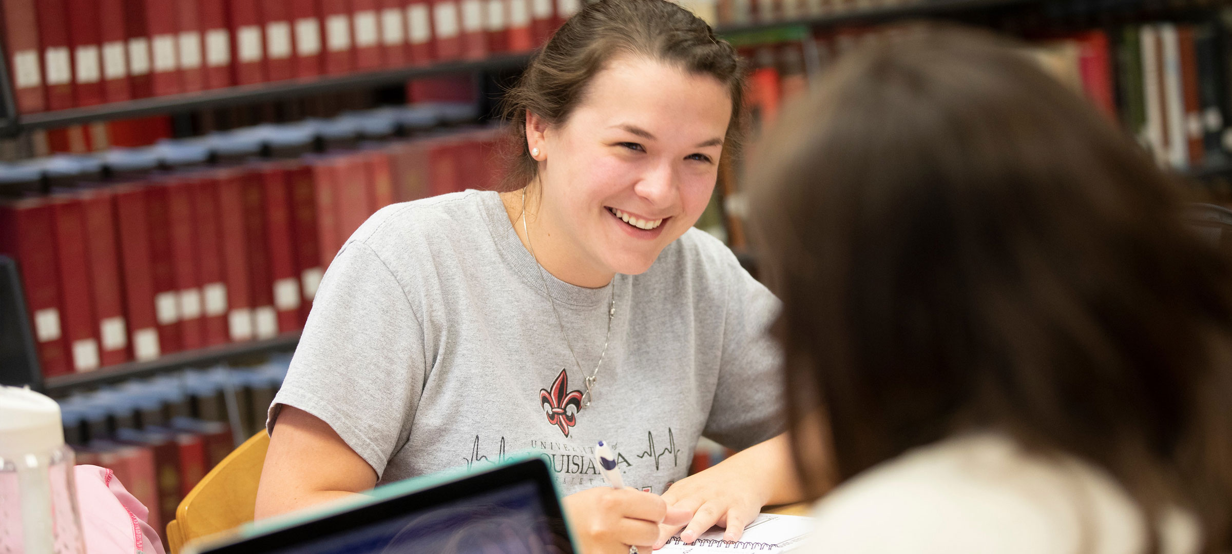 A University of Louisiana at Lafayette student smiling and laughing with a classmate while studying