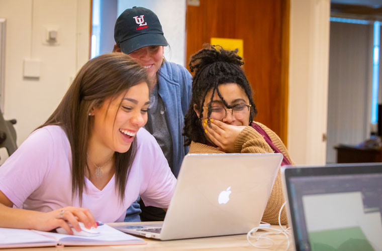 Three University of Louisiana at Lafayette students laughing while studying together