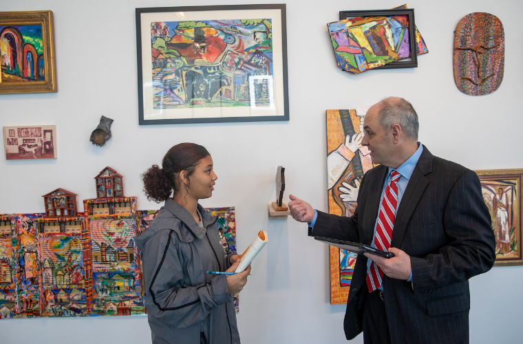 UL Lafayette student talks to professor in front of cultural art display