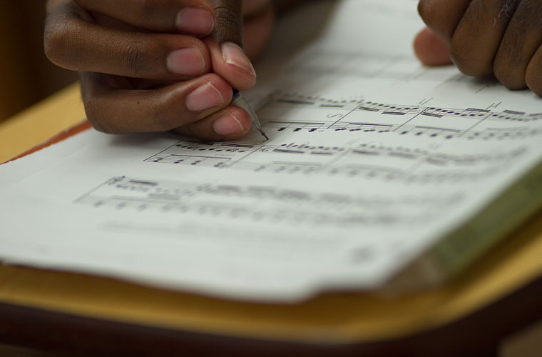 A University of Louisiana at Lafayette music major writes on sheet music with a pencil