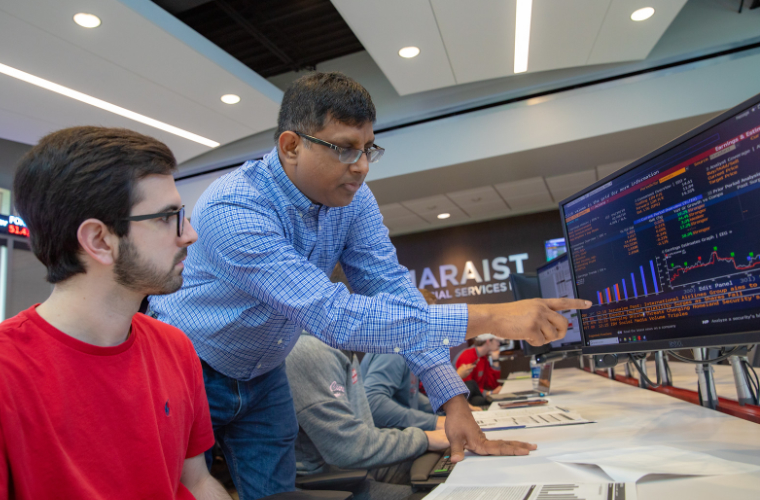 A professor helping a student in the University of Louisiana at Lafayette Maraist Financial Services Lab.