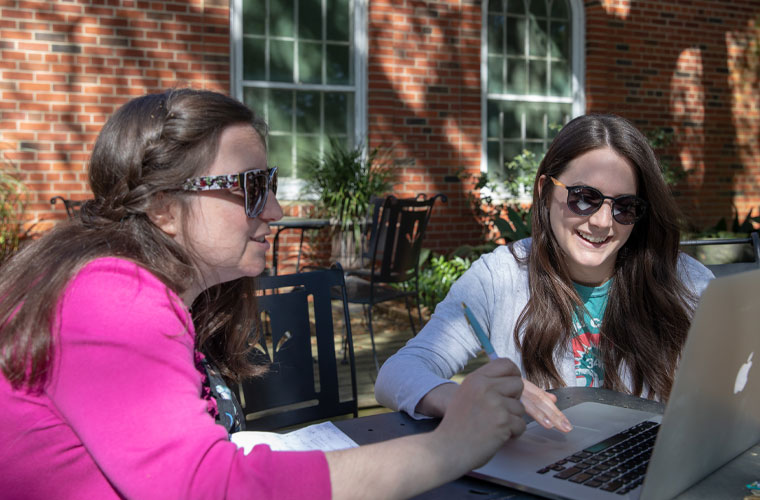 University of Louisiana at Lafayette students sit at a table looking at a laptop screen together