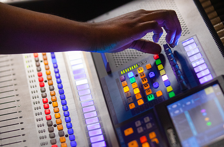 A University of Louisiana at Lafayette music major makes adjustments to audio levels on a control board.