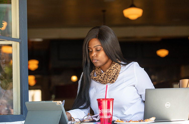 UL Lafayette online student working on her computer at a local business.