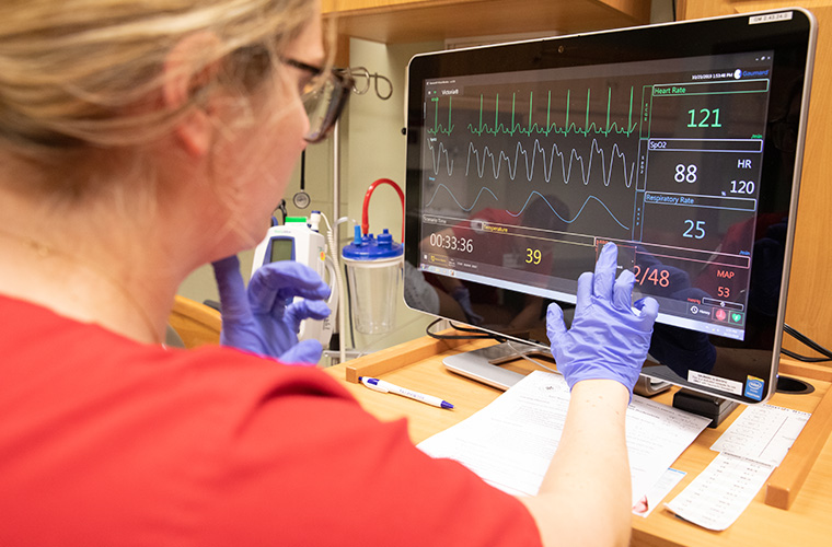 A person using a touch screen to monitor vitals.