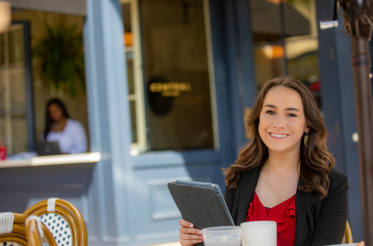 Amanda Terry, Health Services Administration and MBA alumni, studies with a tablet outside of Central Pizza in downtown Lafayette.