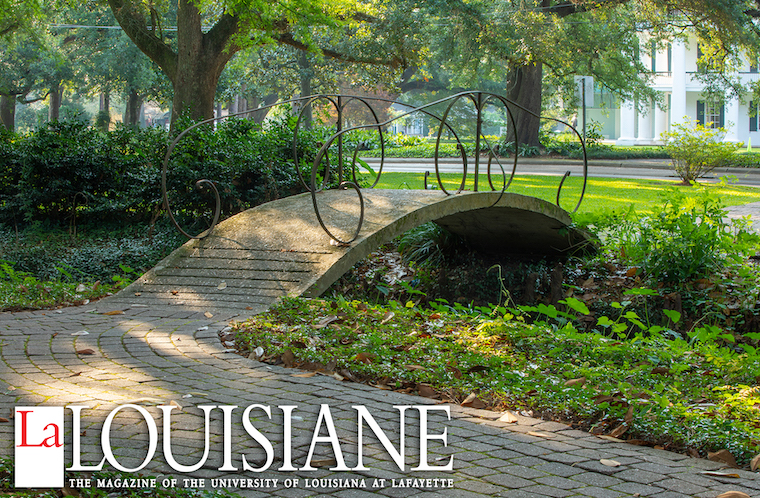 Bridge on the grounds of the Alumni Center with La Louisiane magazine logo
