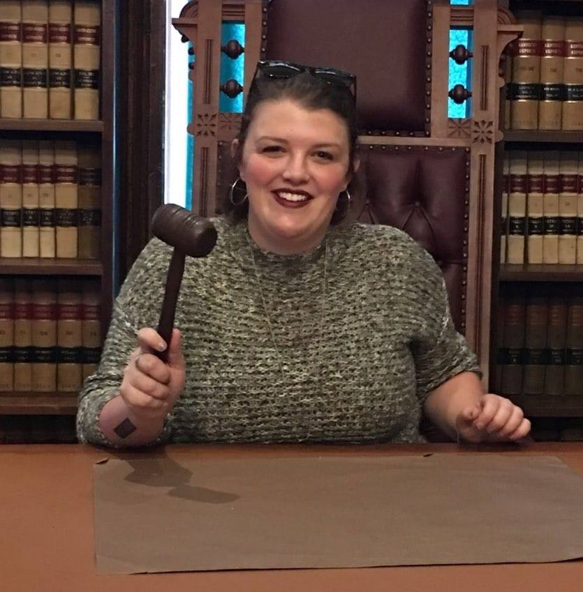 Abbie Deville at a table holding a gavel looking at the camera