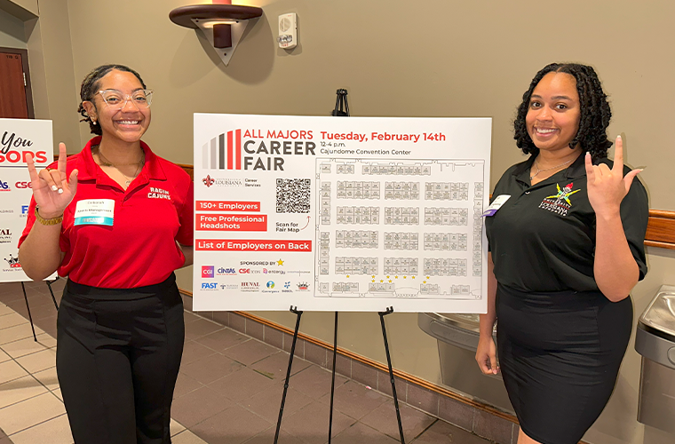 Two UL Lafayette students next to our career fair map exhibiting over 170 employers