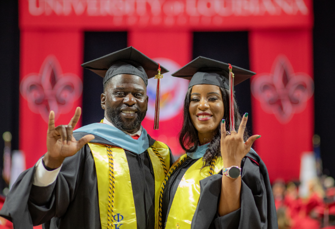 Kreig and Rekeisha Triggs stand in the Cajundome in black cap and gowns during commencement.