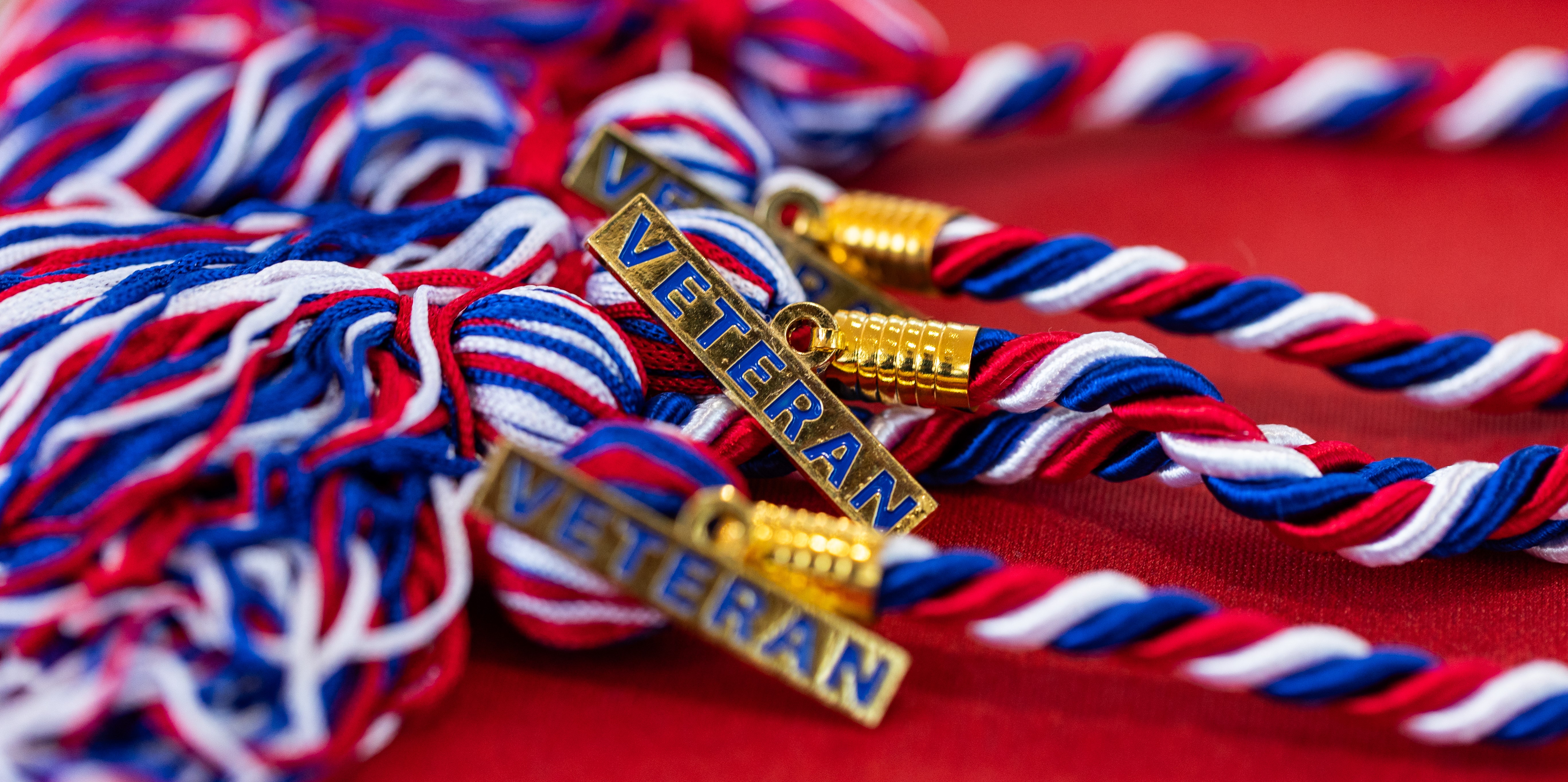 A red, white, and blue graduation cord with a Veteran medallion 