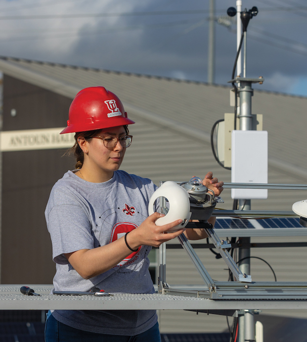 Student Maritza Guadarrama conducting research outside Antoun Hall with a pyrometer, which measures solar energy.