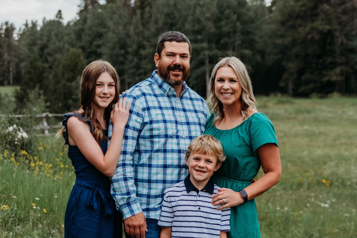 MBA online grad Jonathan Boudreaux smiles for outdoor family photo with wife, daughter, and son