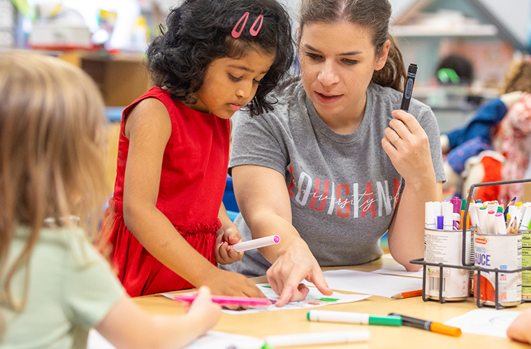 Child Development Center teacher and students drawing