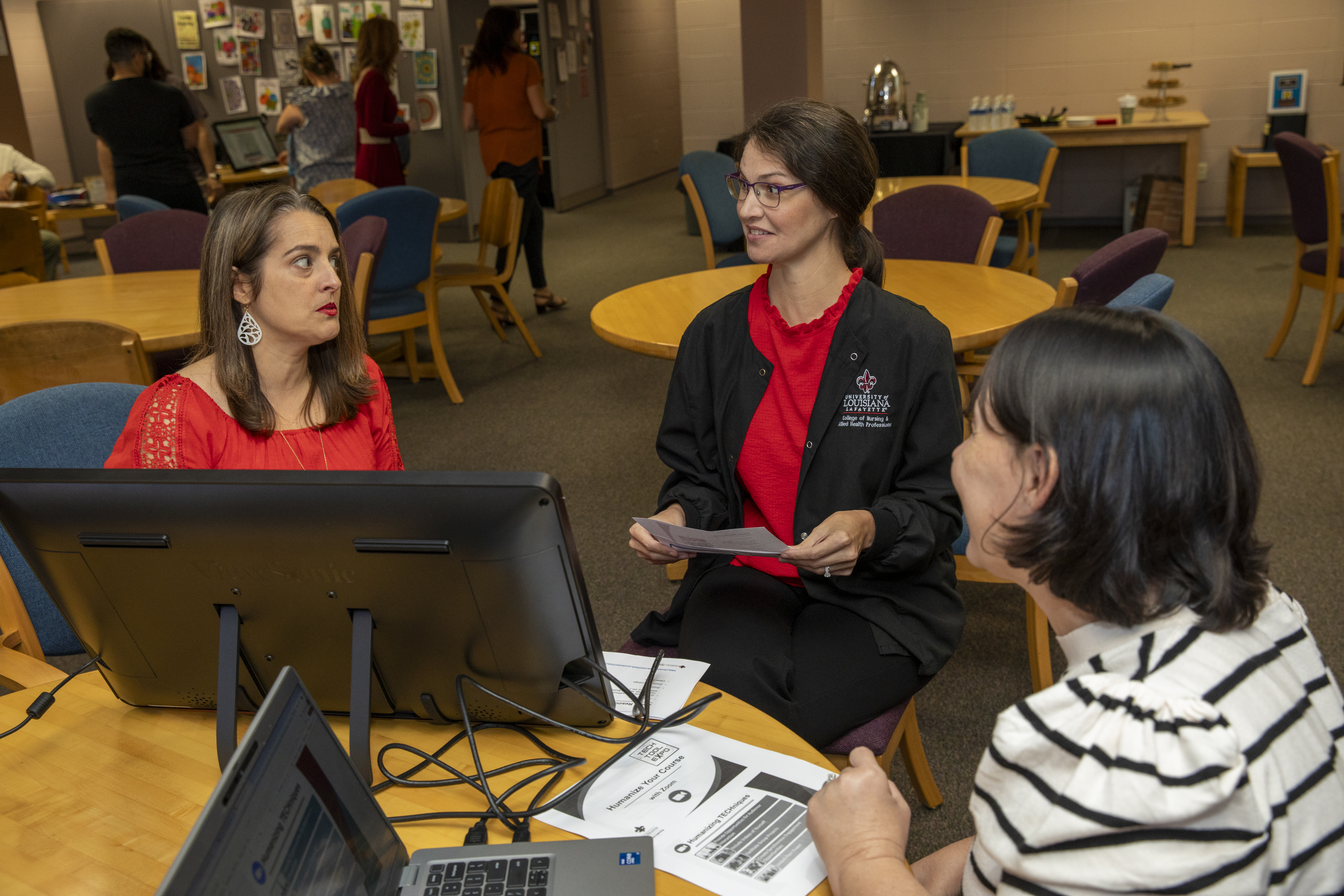 Two faculty members sit with Instructional Designer Alyse Hagan as she presents on a computer monitor.