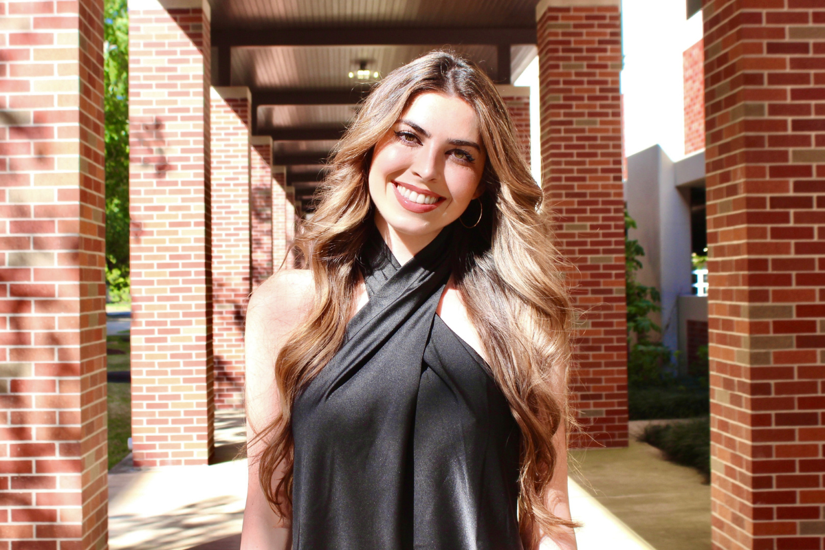 Online M.S. in Informatics graduate, Kaitlin Lange, smiles for photo under a UL Lafayette walkway