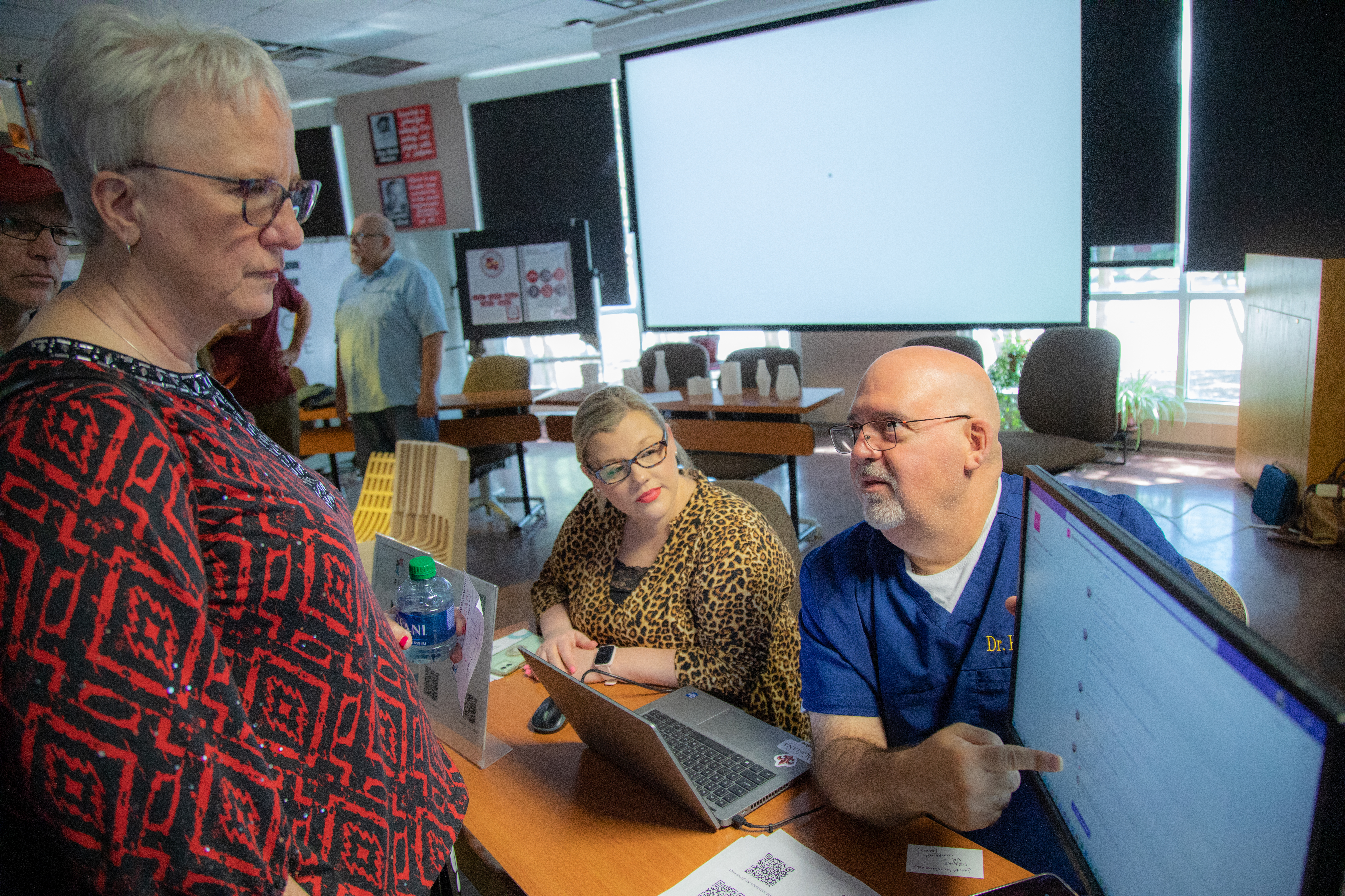 Penny Powell, Latasha Holt, and Robert Garrie gather around a computer monitor as Robert Garrie explains his Faculty Learning Community's research.