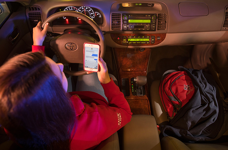 Student checking ENS text message in car in parking lot