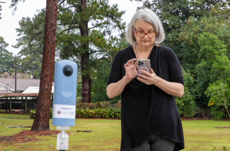 Renee Fiser uses her cell phone to record remotely using the Ricoh Theta SC2 360 Camera.