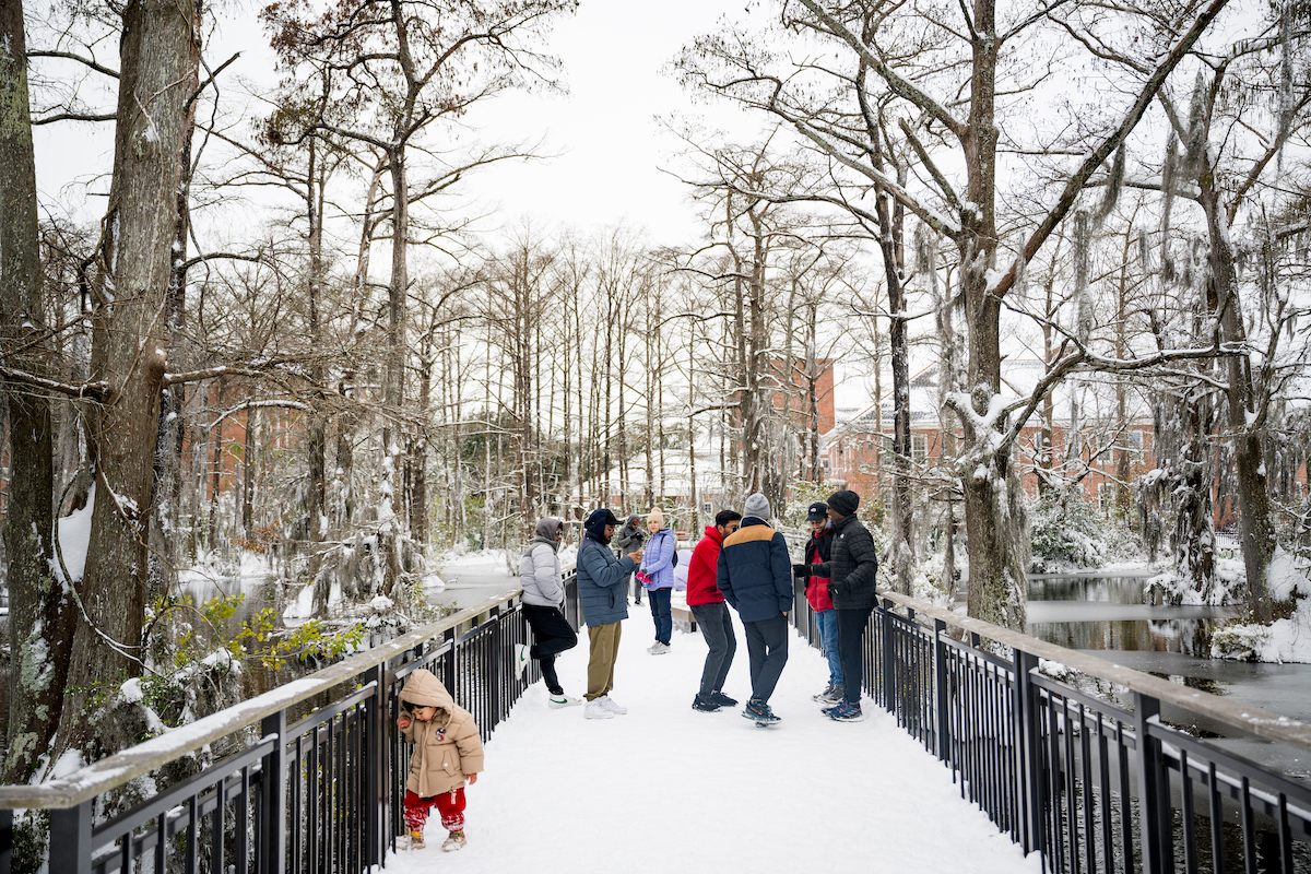 People stand on the Cypress Lake pier in the snow.