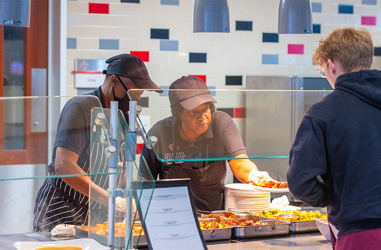 UL Lafayette Campus Food Services handing a plate of food to a student.