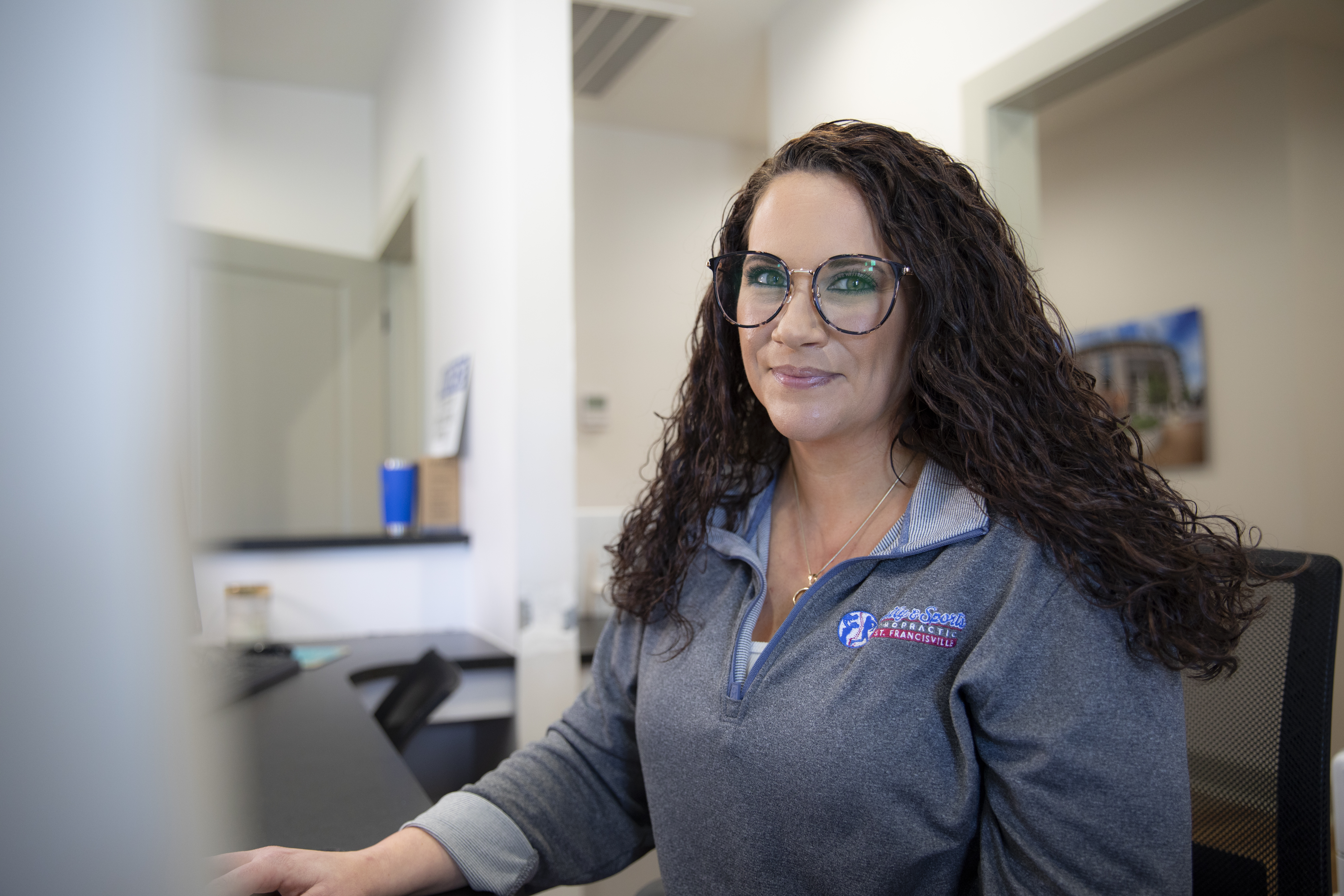 Health Services Administration graduate Sarah Beard smiles at the front desk of Family & Sports Chiropractic.