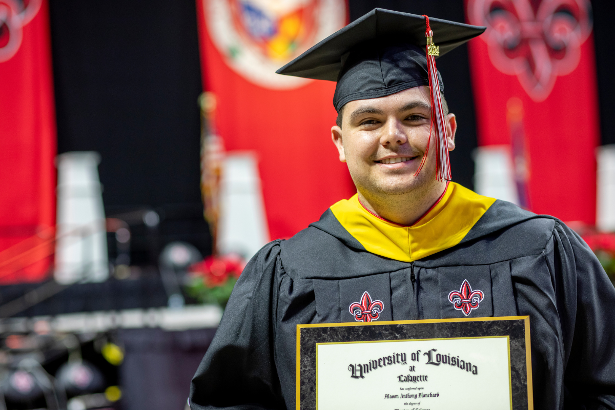 Mason Blanchard smiles for a photo with his M.S. in Systems Technology diploma at UL Lafayette's Fall 2024 Commencement.