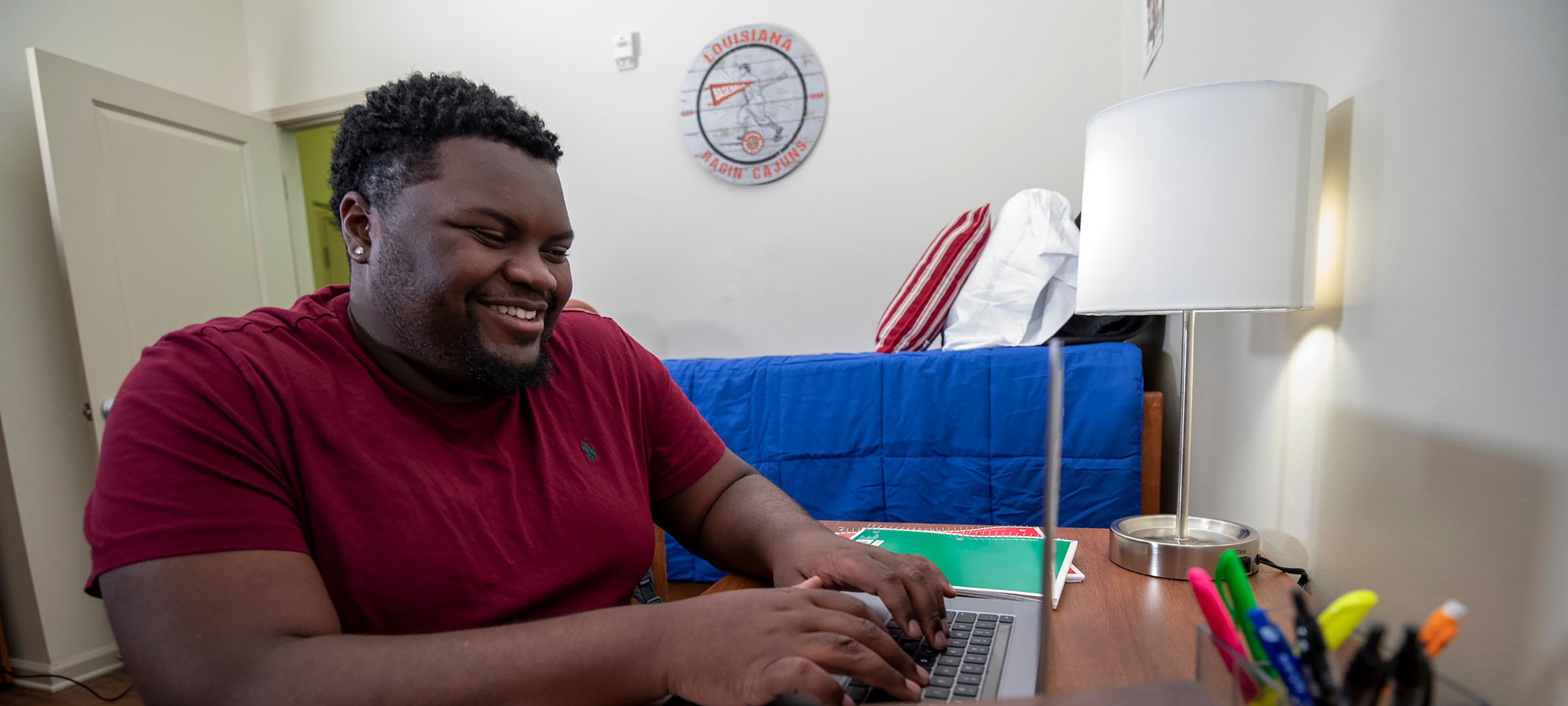 student in dorm room using laptop