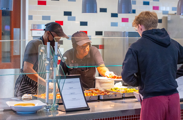 Student grabs a lunch plate from the cafeteria staff in Cypress Lake dining hall