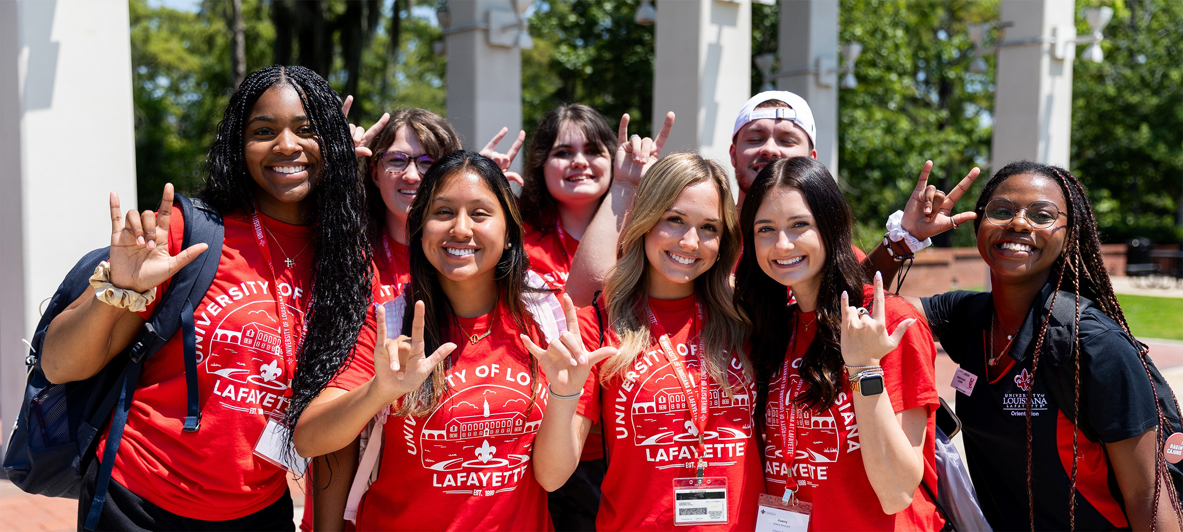 Group of happy UL Lafayette orientation staff holding up "UL" hand signs