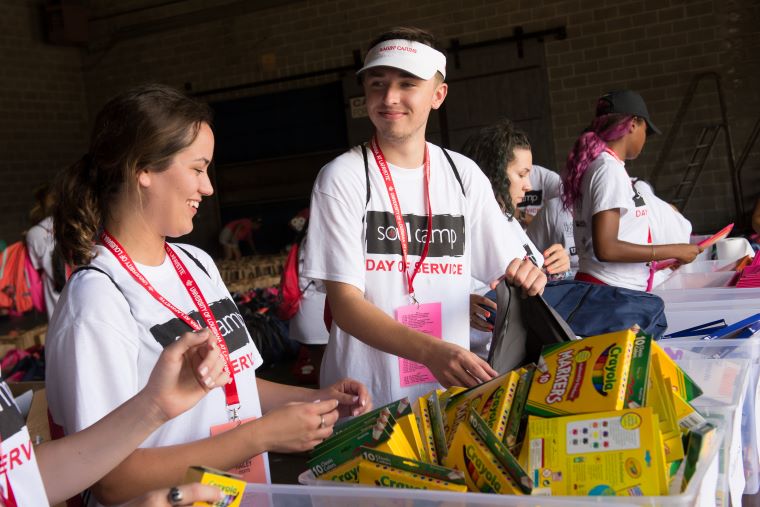 Students in SOUL Camp shirts sort through school supplies during a service project