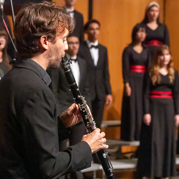 UL student playing clarinet in front of the choir on stage