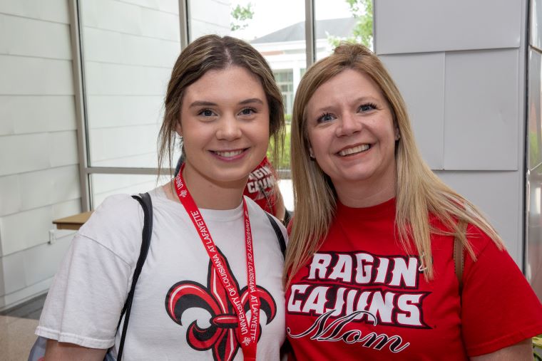 A new student poses with her mother who is wearing a Ragin' Cajuns Mom t-shirt