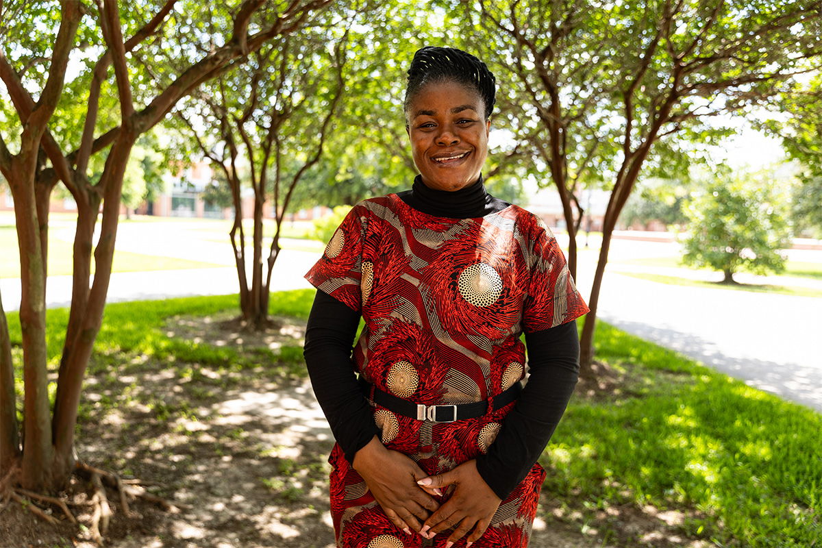 Nchedo Nwankwor smiling in front of trees.