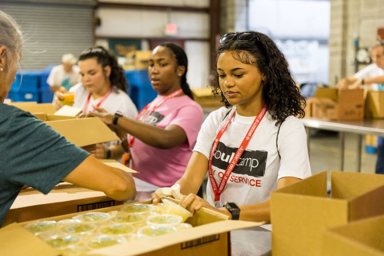SOUL Camp attendees sort through boxes of food in a warehouse during a service project 