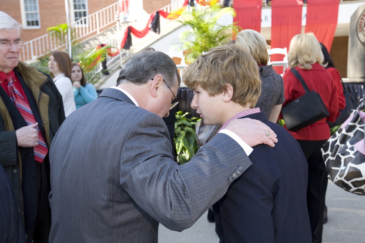 Adam Savoie, right, checks with his dad, UL Lafayette President Dr. Joseph Savoie, at an ecumenical prayer service.