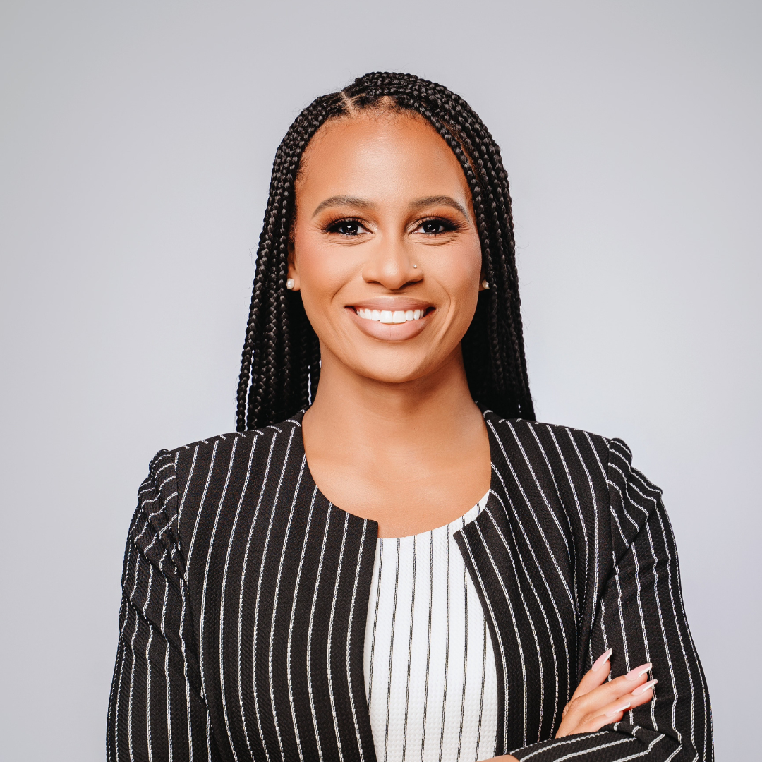 Alumni of the online MEd program smiles for headshot in an arms-crossed pose.