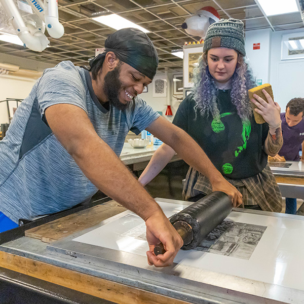 UL Lafayette printmaking students rolling ink over their carved stamp.