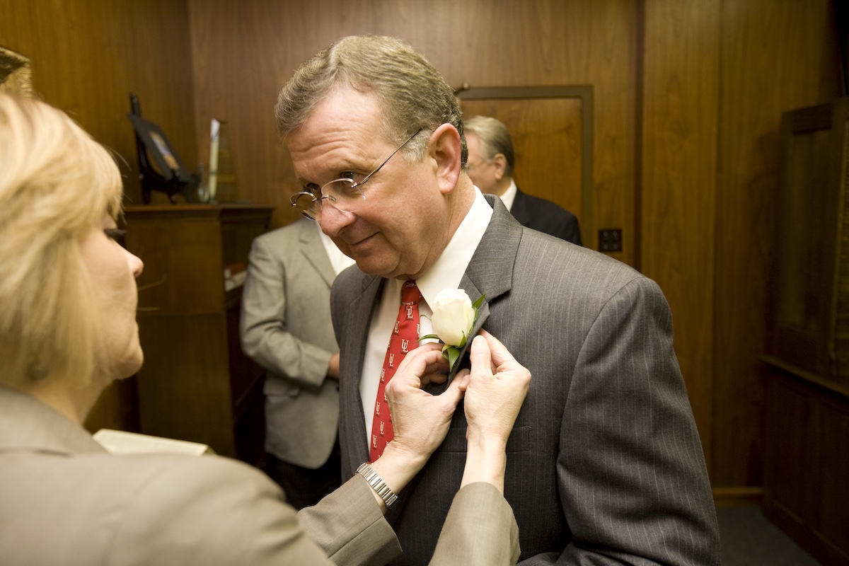 Liz Landry, executive assistant to the president, pins a boutonniere onto Dr. Joseph Savoie's lapel on the morning of his inauguration.