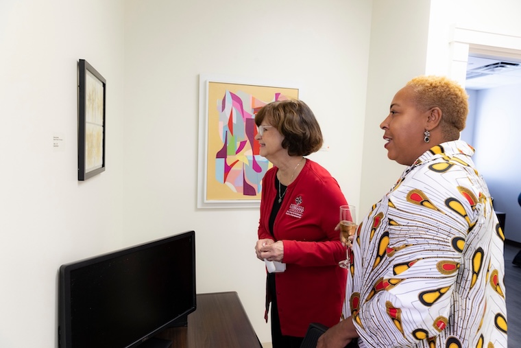 Two women gaze at a painting hung in the Moody Hall Gallery