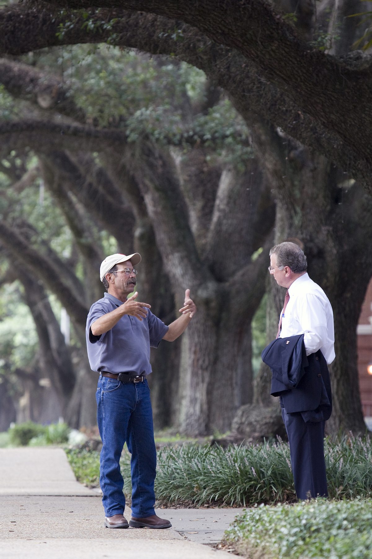 John Broderick, left, manager of ground services at UL Lafayette, and President Dr. Joseph Savoie chat in the shade of oaks along St. Mary Boulevard.