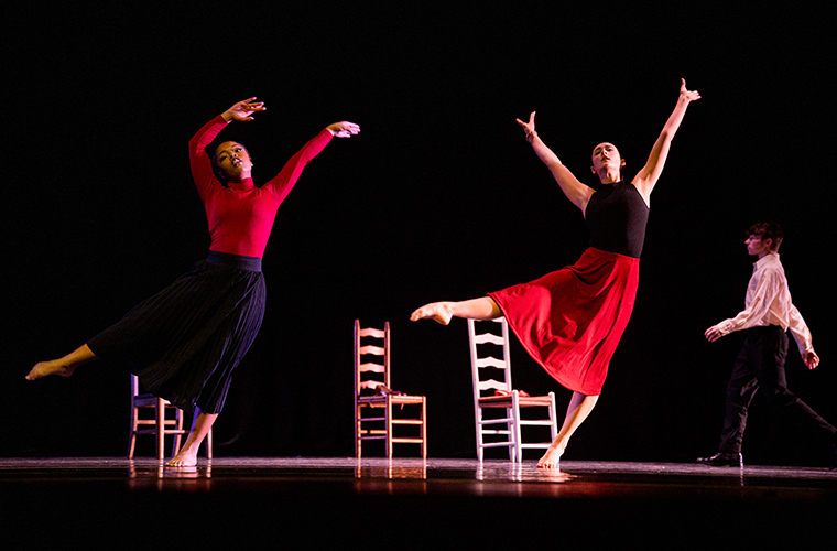 Two students lifting their legs during a dance performance