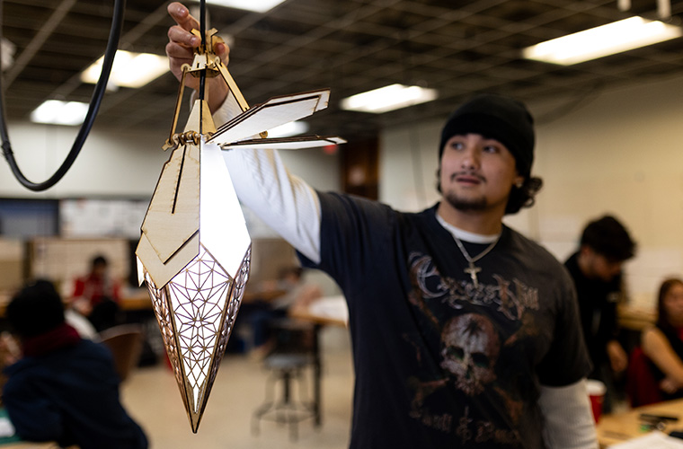 UL Lafayette industrial design student holding up a laser cut wood pendant light.