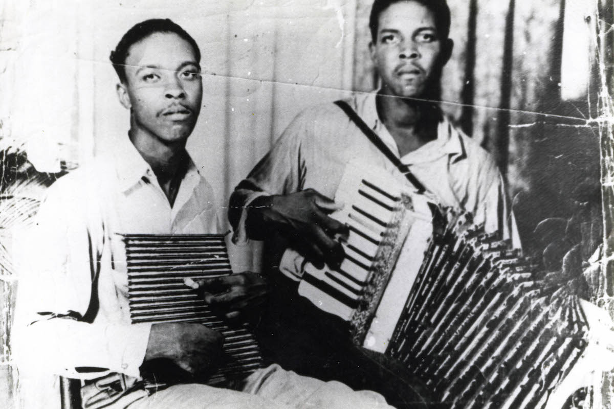 The Chenier brothers, Cleveland and Clifton pose with an accordian and washboard in a black and white photograph.